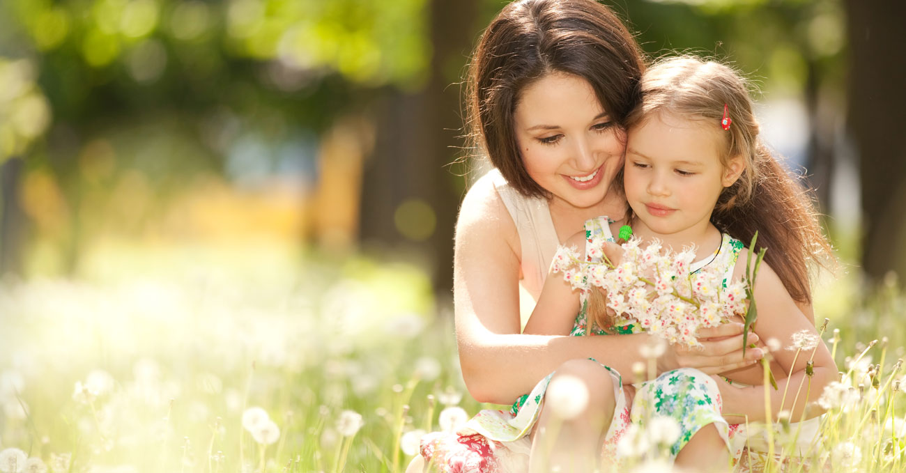 Smiling young woman picking flowers with small girl