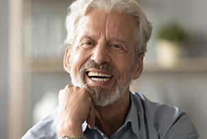 An older man smiling and enjoying his dentures