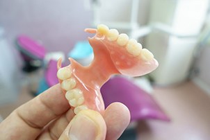 A closeup of a removable denture held by a hand