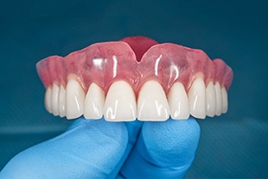 Denture dentist in Centerville holding a denture