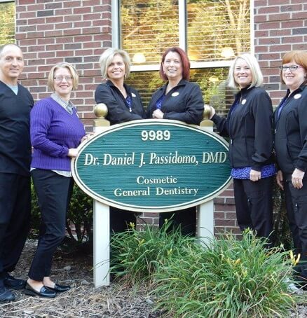 Smiling dental team next to exterior sign of Daniel J. Passidomo, DMD in Centerville