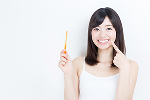Woman holding toothbrush pointing to white smile