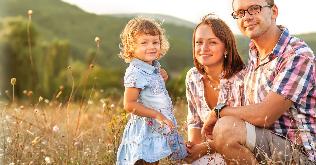 Smiling man and woman with small girl in a field