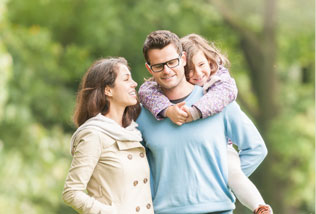 Smiling girl riding on young man's back, standing next to smiling woman