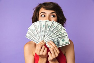 Woman fanning several bills over her smile