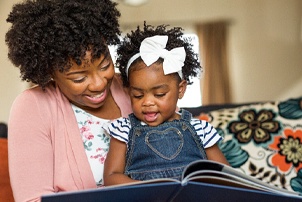 a parent reading their child a book to prepare them to visit their dentist in Centerville