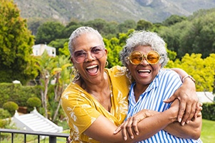Two woman smiling and hugging each other outside