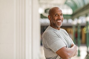 Man in gray shirt smiling outside