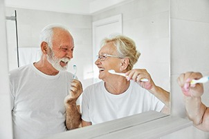 Senior couple smiling while brushing their teeth