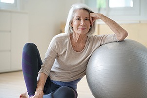 Senior woman smiling while resting against balance ball