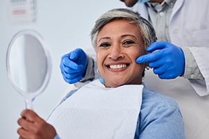 Woman smiling while holding small mirror