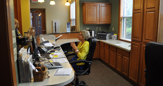 Dental team member sitting behind reception desk talking to a patient