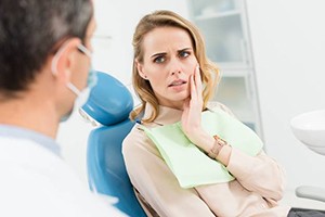 A young woman in the dentist chair holding her cheek
