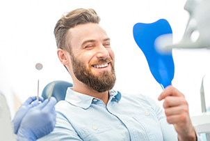 Man looking at healthy smile in mirror