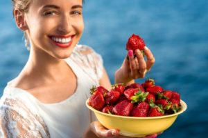 Woman holding strawberries after teeth whitening.