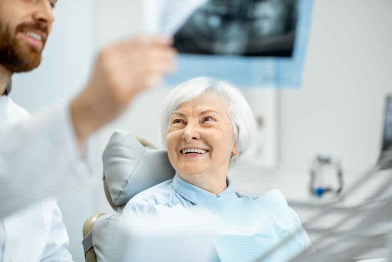 Implant dentist showing smiling patient their X-ray