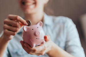 Woman slipping a coin into her piggy bank