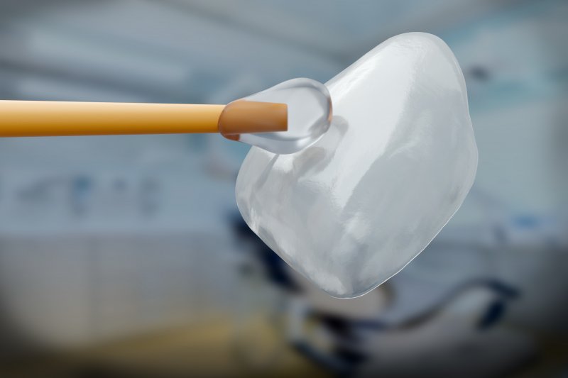 A 3D illustration of a dental veneer and an applicator