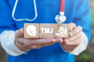 Medical professional holding TMJ disorder illustration.